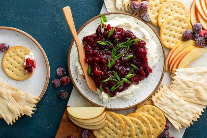 Cranberry cream cheese dip on a platter next to crackers and sliced apples