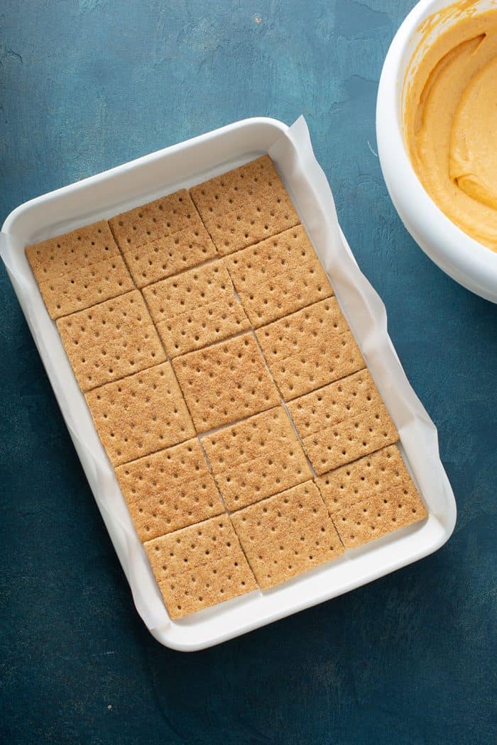 Layer of cinnamon graham crackers in the bottom of a white cake pan