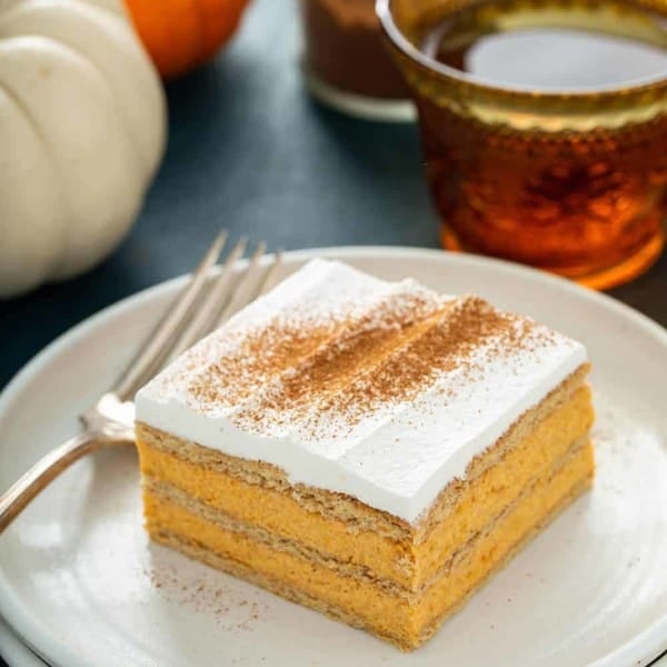 Slice of pumpkin eclair cake next to a fork on a white plate