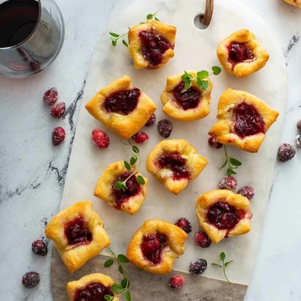 Overhead view of cranberry brie bites on a marble and wood serving board