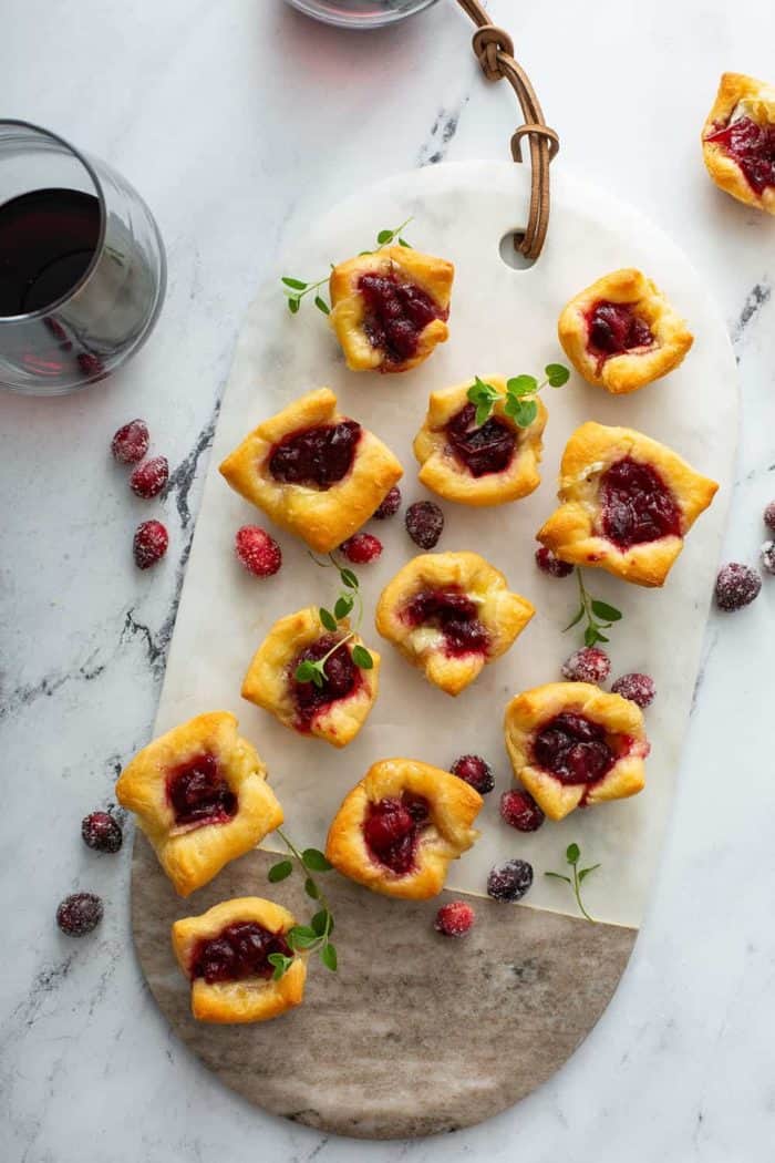 Overhead view of cranberry brie bites on a marble and wood serving board