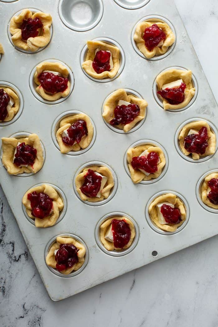 Unbaked cranberry brie bites in a mini muffin tin