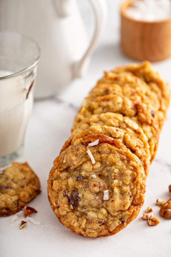 Ambrosia cookies stacked in a row on a countertop next to a glass of milk