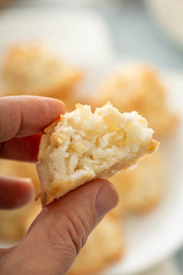 Hand holding up a coconut macaroon with a bite taken out of it