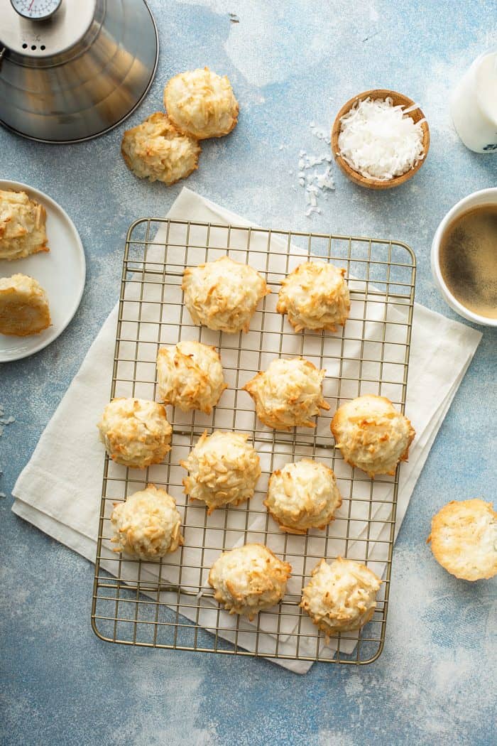 Coconut macaroons cooling on a wire rack surrounded by macaroon ingredients