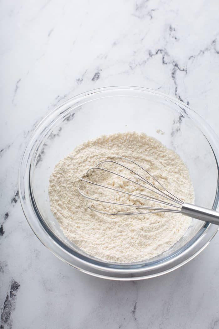 Cookie dry ingredients whisked together in a glass mixing bowl on a marble counter