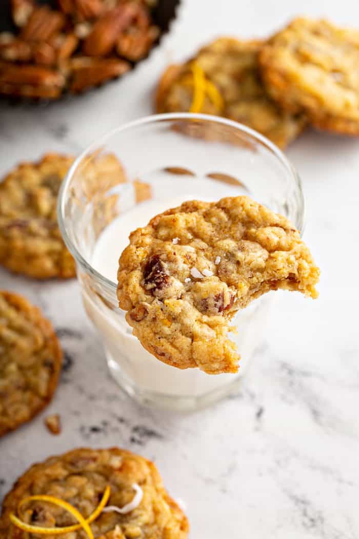 Ambrosia cookie with a bite taken out of it propped on the edge of a glass of milk