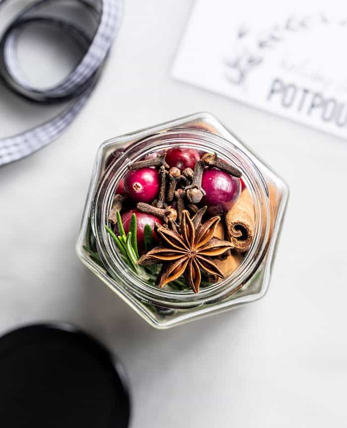 Overhead view of an open jar filled with stovetop potpourri on a marble counter