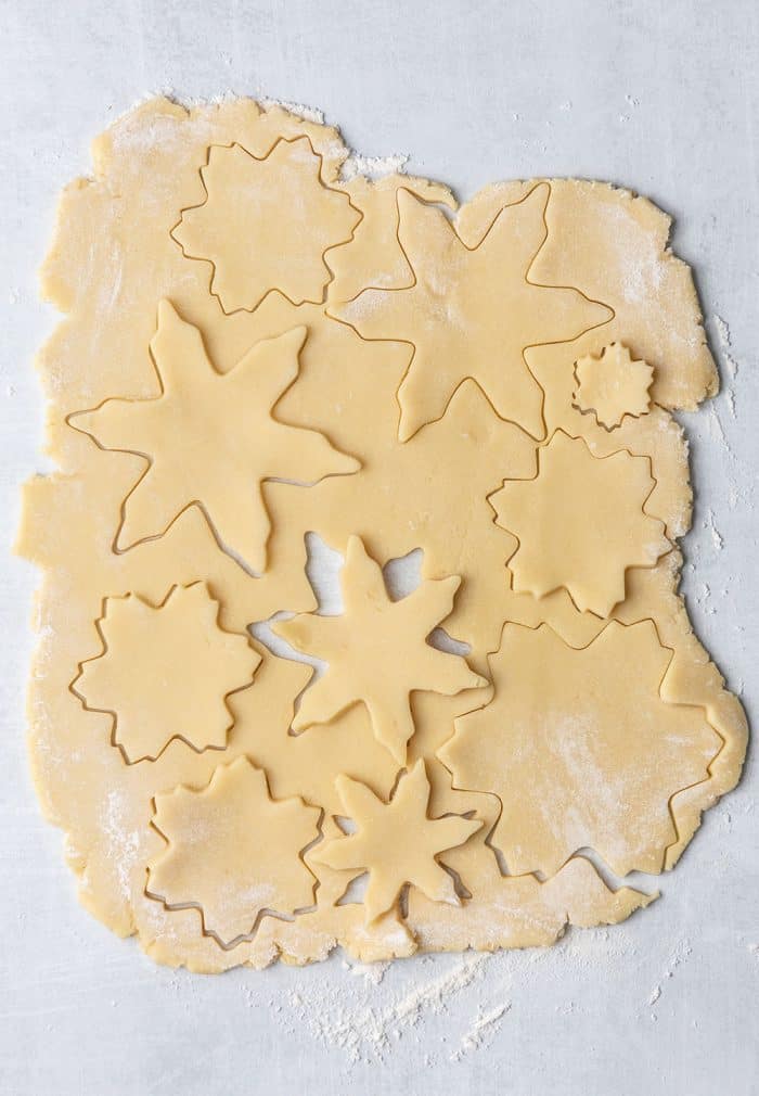 Sugar cookie dough rolled out, with snowflake shapes cut into it