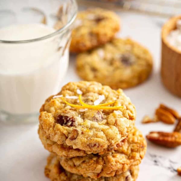 Stack of 4 ambrosia cookies on a marble counter with a glass of milk in the background