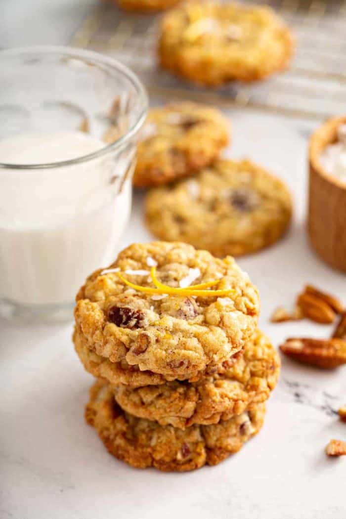 Stack of 4 ambrosia cookies on a marble counter with a glass of milk in the background