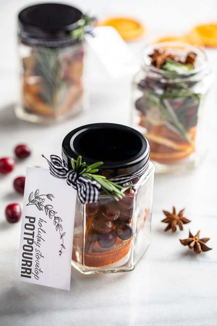 Stovetop potpourri in 3 glass jars tied with gift tags on a marble counter