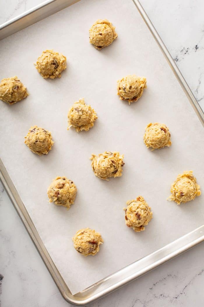 Unbaked ambrosia cookies on a parchment-lined baking sheet