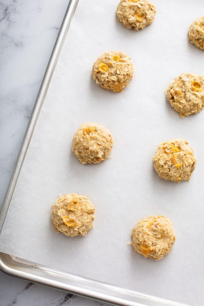 unbaked cornflake cookie dough portioned onto a parchment lined baking sheet