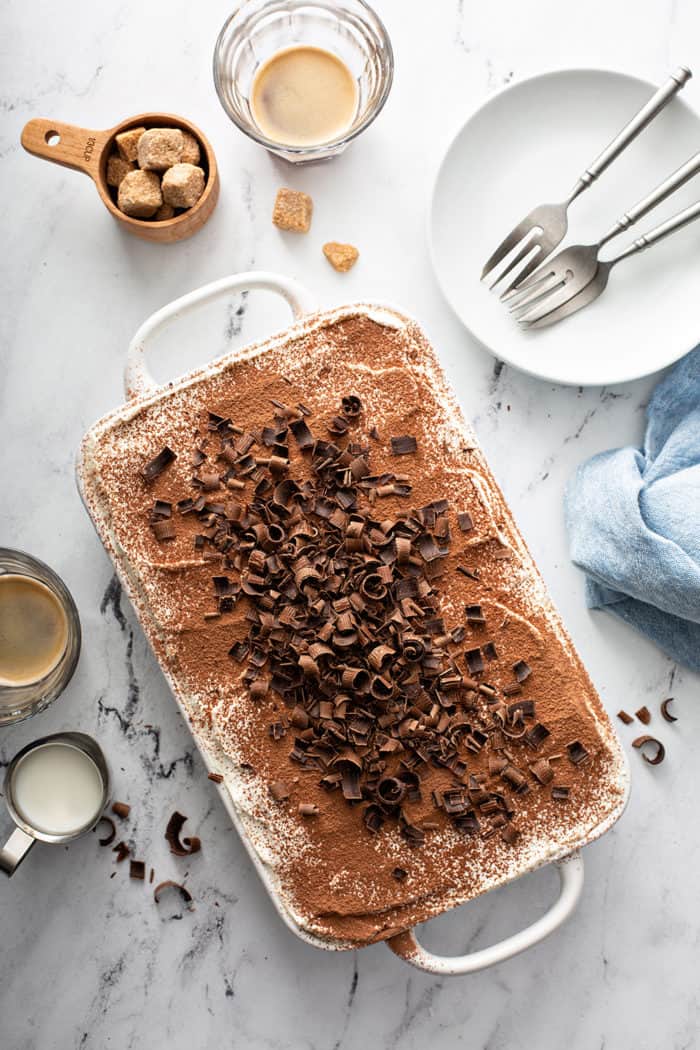 Overhead view of assembled tiramisu topped with cocoa powder and chocolate curls