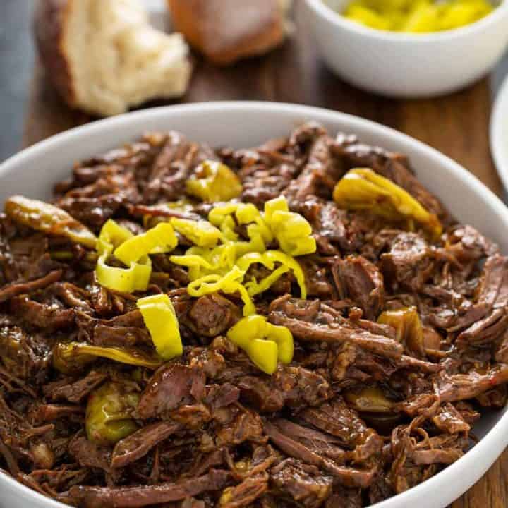 Mississippi pot roast topped with sliced pepperoncini peppers in a white serving bowl