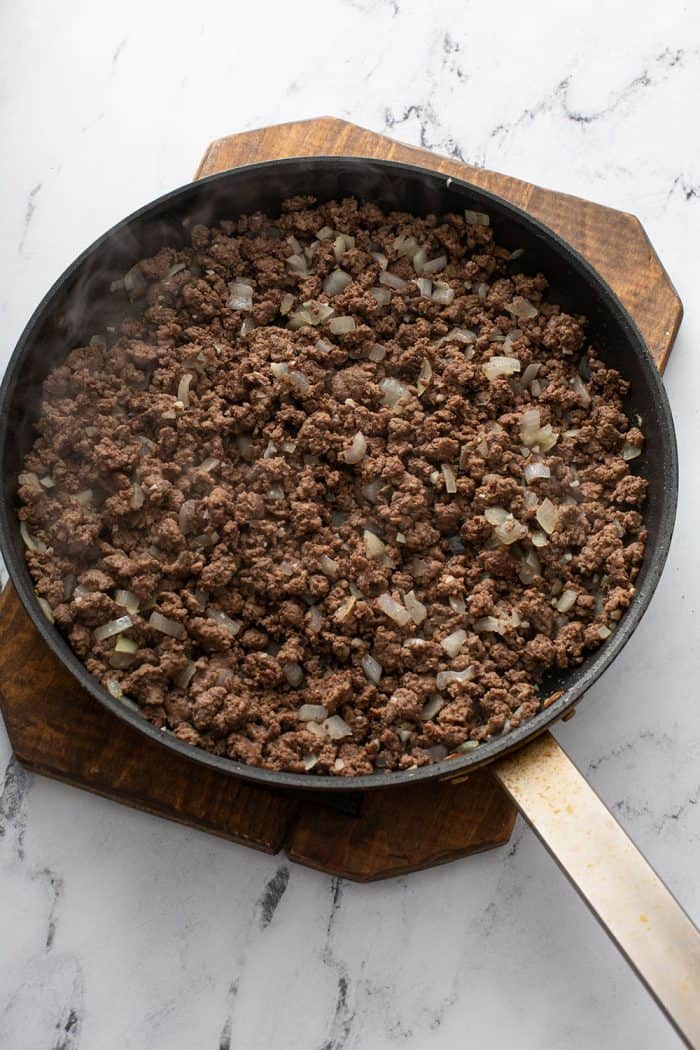 Cooked slider meat in a skillet on a wooden trivet