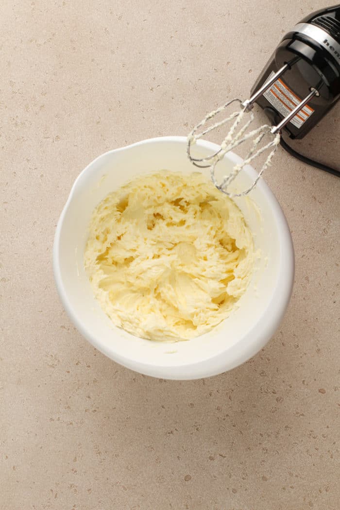 Cream cheese and butter beaten together in a white bowl.