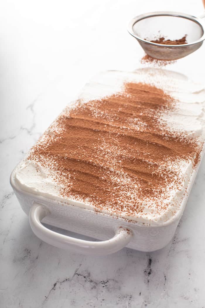 Cocoa powder being dusted on top of tiramisu