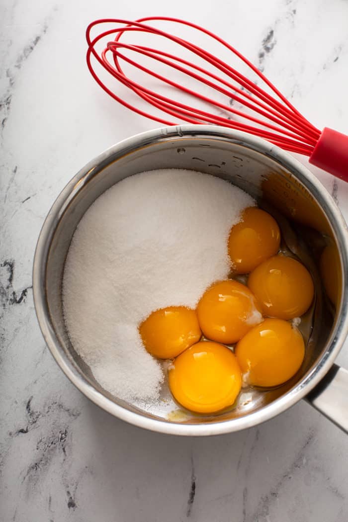 Egg yolks and sugar in a saucepan on a marble counter