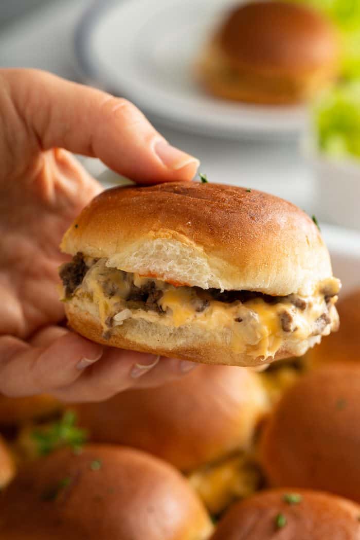 Hand holding a cheeseburger slider up to the camera