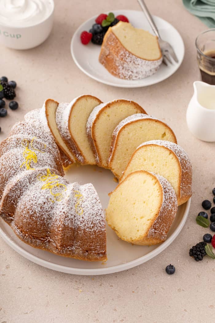 Sliced cream cheese pound cake on a white platter, dusted with powdered sugar.