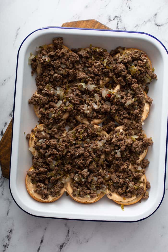 Slider meat spooned over the bottoms of slider buns in a white baking dish