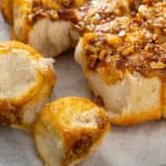 Close up of pecan sticky buns pulled apart on a piece of parchment paper