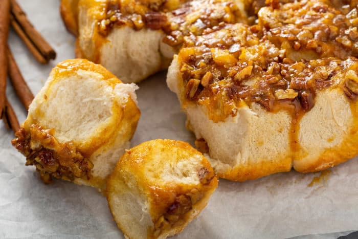 Close up of pecan sticky buns pulled apart on a piece of parchment paper