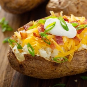 Loaded baked potato on a wooden cutting board