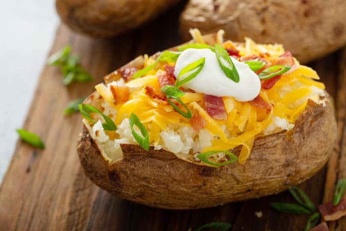 Loaded baked potato on a wooden cutting board