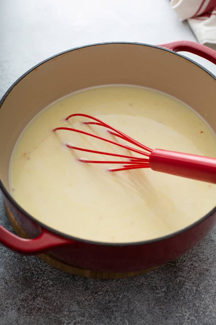 Whisk stirring milk and chicken stock in a large dutch oven