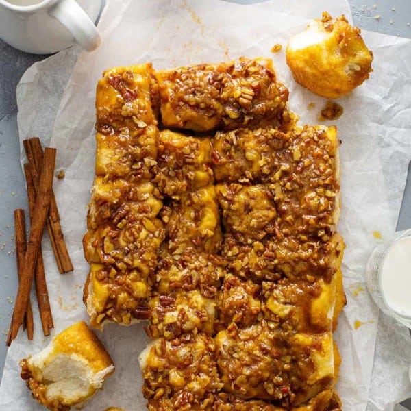 Overhead view of pecan sticky buns on parchment paper next to glasses of milk