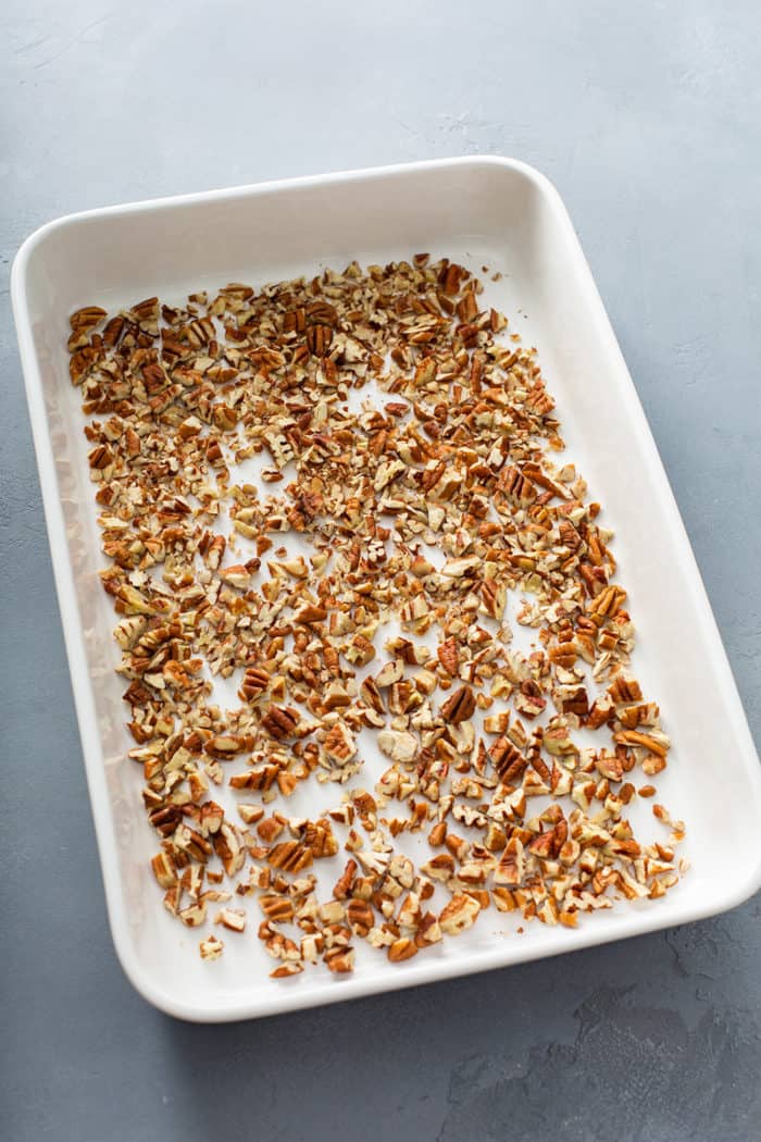 Chopped pecans in the bottom of a white baking dish