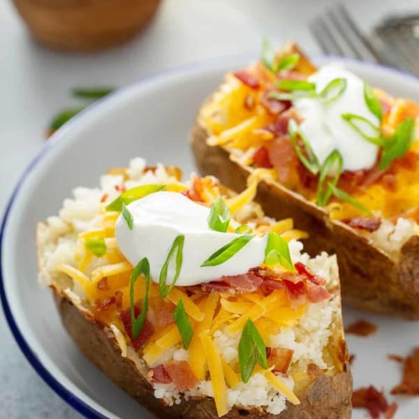 Two loaded baked potatoes on a white plate
