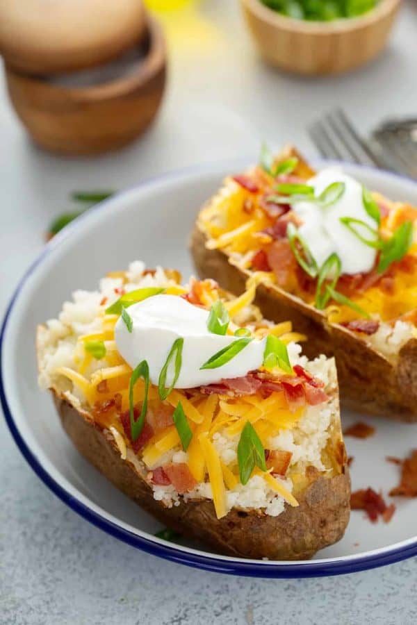 Two loaded baked potatoes on a white plate