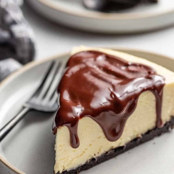 Slice of Baileys cheesecake topped with chocolate ganache on a plate