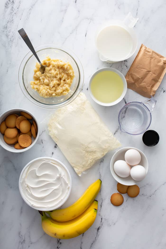 Ingredients for banana pudding poke cake arranged on a marble countertop