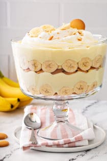 Layered banana pudding in a trifle dish, topped with whipped cream and sliced bananas