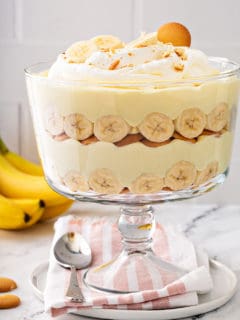 Layered banana pudding in a trifle dish, topped with whipped cream and sliced bananas