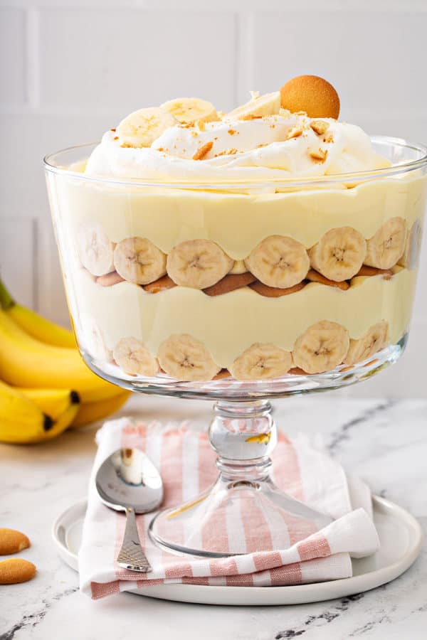 Layered banana pudding in a trifle dish, topped with whipped cream and sliced bananas