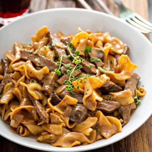 One-Pot Beef Stroganoff in a white bowl, garnished with fresh thyme