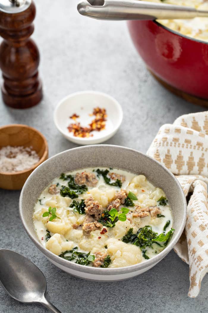 Low carb zuppa toscana in a gray bowl with salt and red pepper flakes in the background