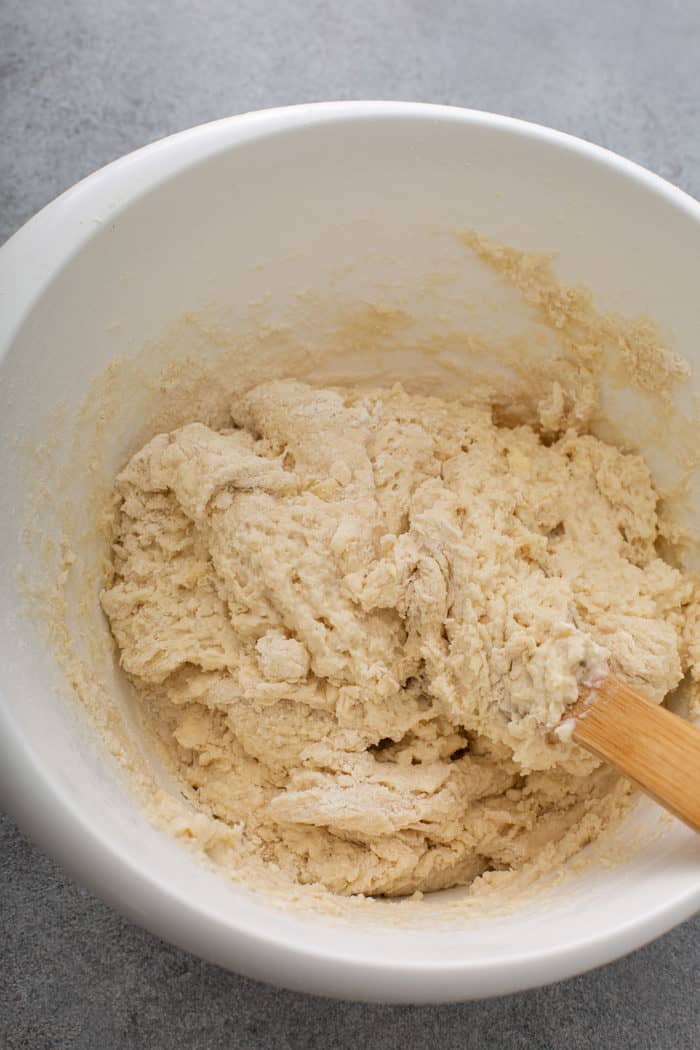 Wooden spoon stirring Irish soda bread dough in a white mixing bowl