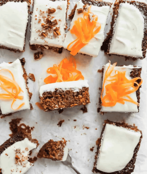 Slices of frosted carrot cake on a piece of parchment paper