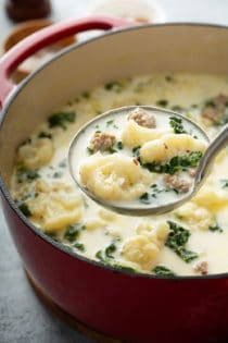 Ladle serving up a portion of low carb zuppa toscana from a large dutch oven of soup