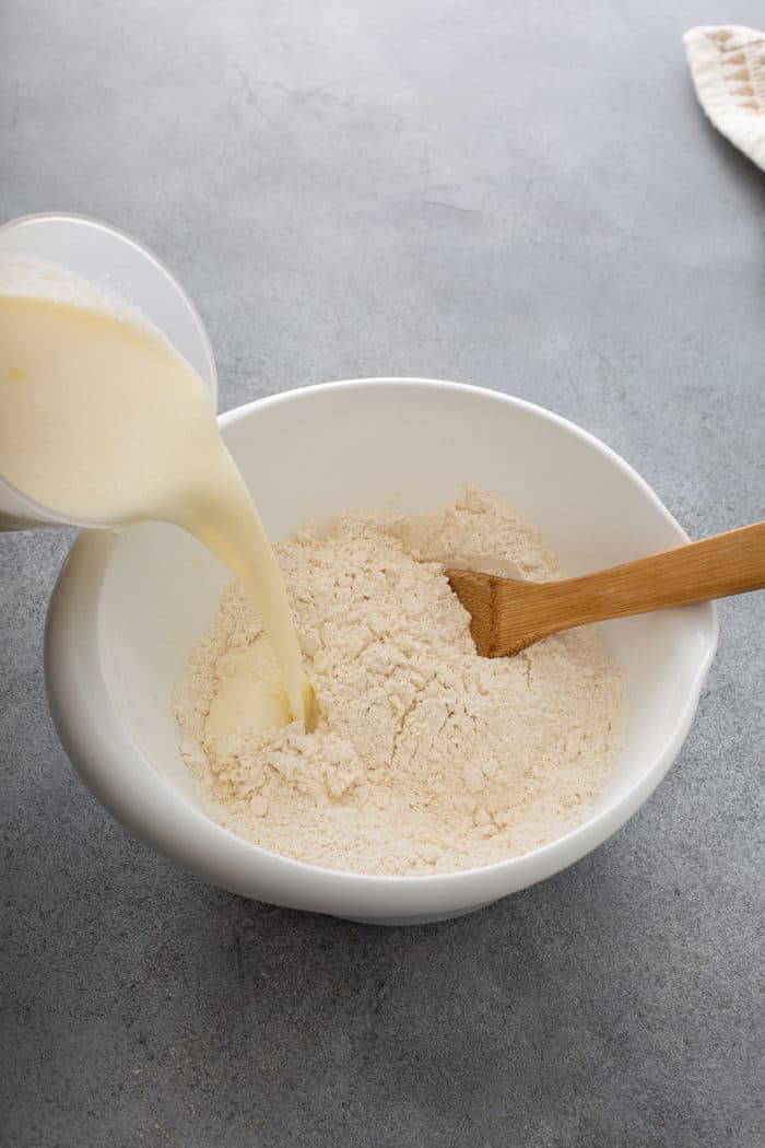 Buttermilk being poured into a bowl of flour for soda bread