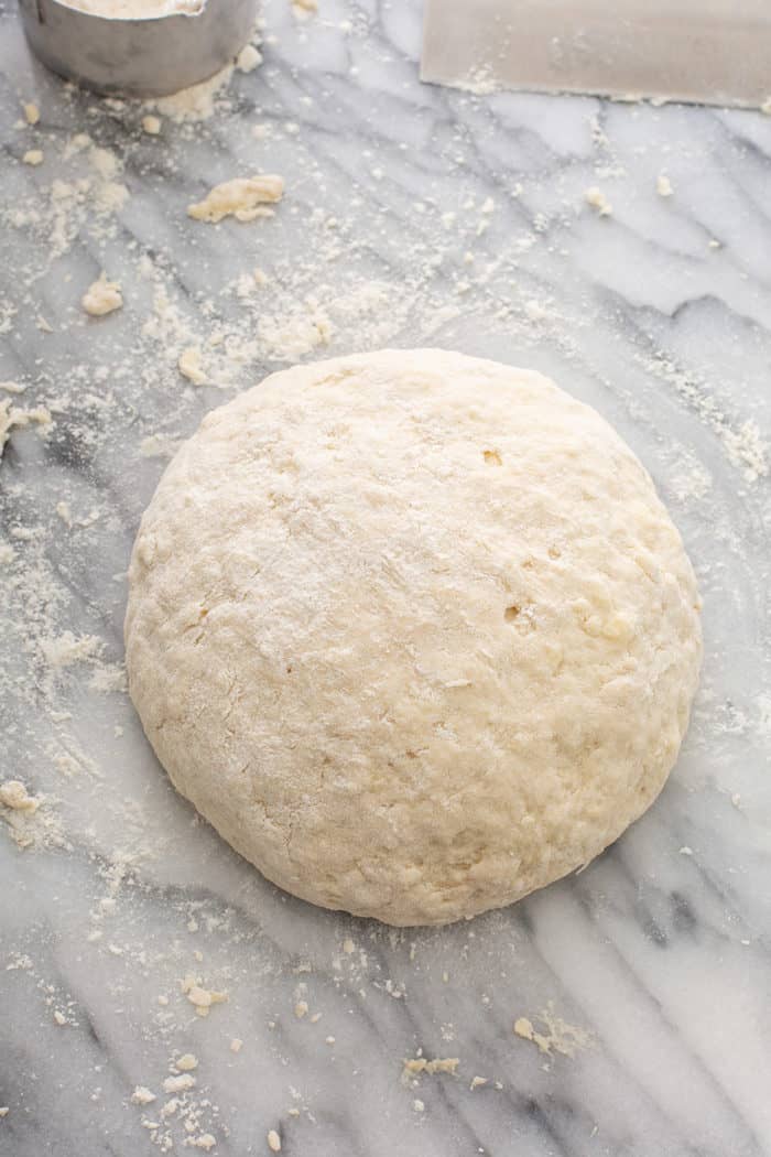 Shaped loaf of irish soda bread on a floured marble surface