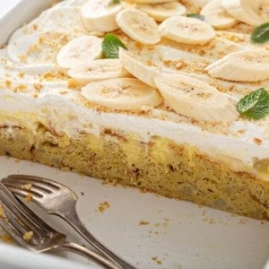 Banana pudding poke cake in a white baking dish with several slices removed to show the inside view of the cake