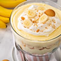 Banana pudding in a trifle dish, topped with whipped cream, bananas, and nilla wafer cookies